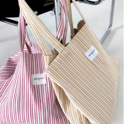 Duas bolsas de tecido listrado penduradas numa cadeira metálica.