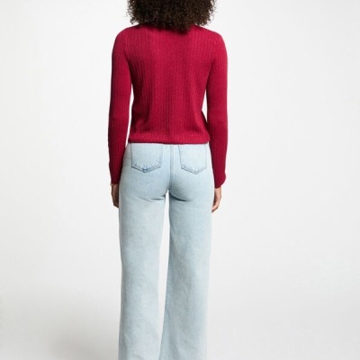 Pessoa de costas com camisola vermelha e calças de ganga azul clara