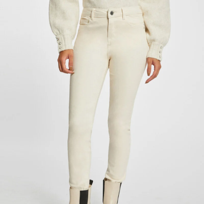 Calças justas creme usadas com botas creme e camisola de malha creme