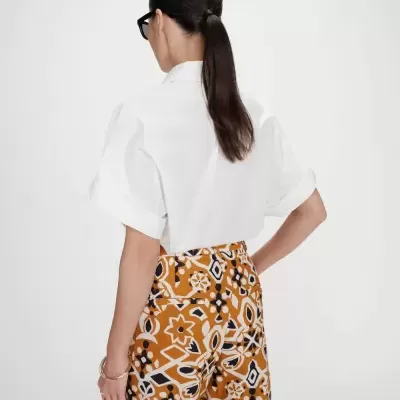 Camisa branca de manga curta e calças com padrão geométrico e floral em cor ferrugem, branco e preto