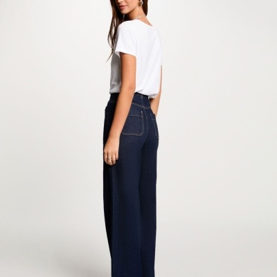 Mulher com t-shirt branca e calças de ganga azul escuras largas