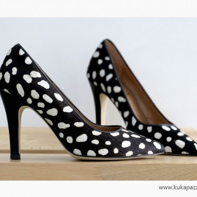 Sapatos de salto alto preto com manchas brancas apresentados sobre madeira