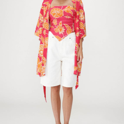 Conjunto feminino com blusa e kimono rosa com padrão floral laranja e calções brancos compridos até ao joelho