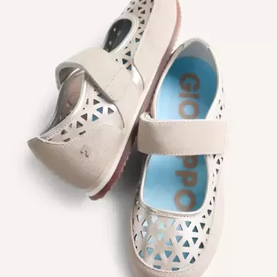 Sapatos infantis Mary Jane bege com recortes triangulares e sola rosa.