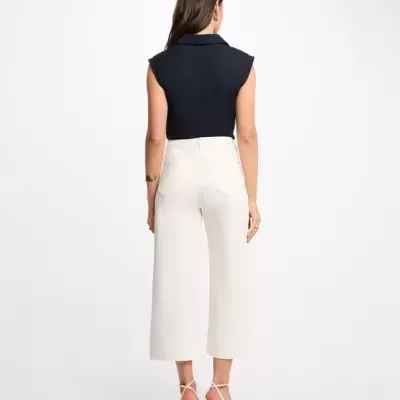 Calças brancas largas cropped e camisa azul escura sem mangas vista de costas