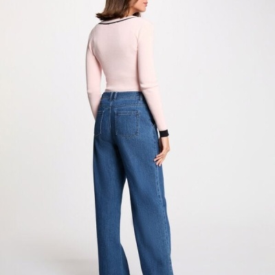 Mulher vista de costas com calças de ganga largas azuis, camisola rosa e botas pretas