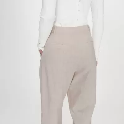 Calças bege claras com textura e camisola branca de malha canelada com botões prateados.