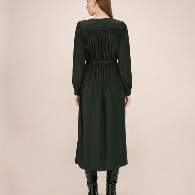 Vestido comprido verde escuro de costas com botas pretas