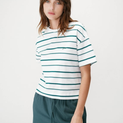 T-shirt branca com riscas verdes e calças verdes escuras em modelo feminina.