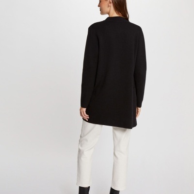 Blazer preto de mulher visto de costas com calças brancas e botins pretos