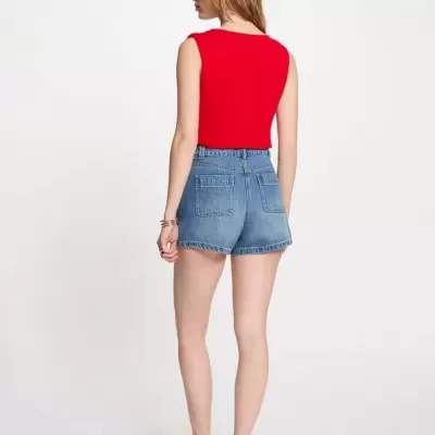Mulher de costas com top vermelho e calções de ganga azuis