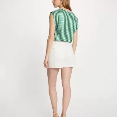 Mulher de costas com top às riscas verde e branco, calções brancos e sandálias amarelas