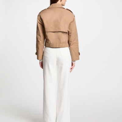 Casaco curto bege visto de costas, com calças brancas largas