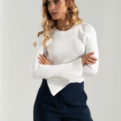 Mulher com camisola branca de malha canelada e calças azuis escuras