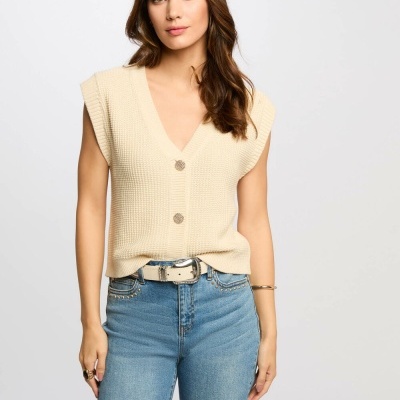 Camisola de malha bege com botões grandes e calças de ganga azul claro.