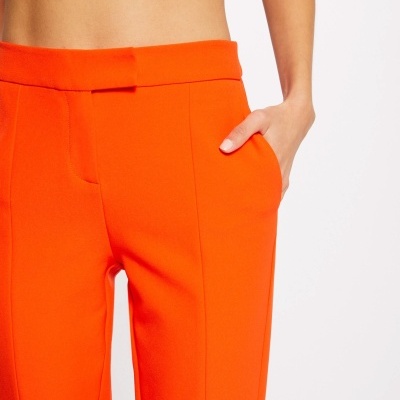 Calças laranja vibrantes com bolso lateral e fecho oculto