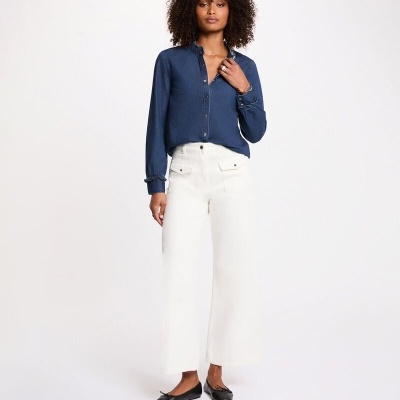 Calças brancas largas com bolso, blusa azul de botões e sapatos pretos rasos