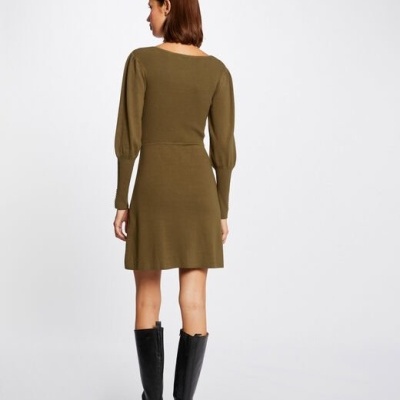 Vestido curto de malha verde-oliva com mangas bufantes e botas pretas, visto de costas