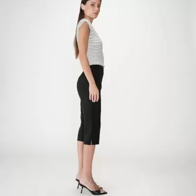 Mulher de perfil com blusa riscada e calças pretas, sapatos de salto, fundo branco