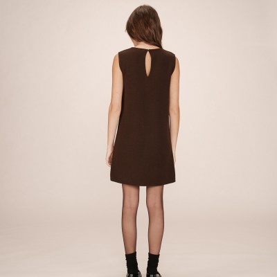 Mulher vista de costas a usar vestido preto sem mangas, meias pretas e sapatos pretos