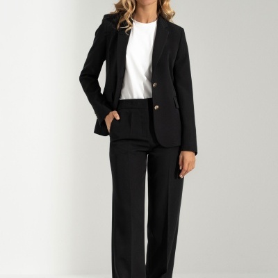 Mulher vestindo fato feminino preto e camisa branca com ténis brancos.