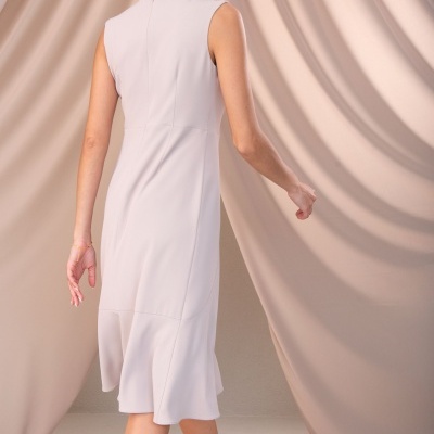 Vestido midi bege claro sem mangas numa modelo vista pelas costas com cortinas bege ao fundo