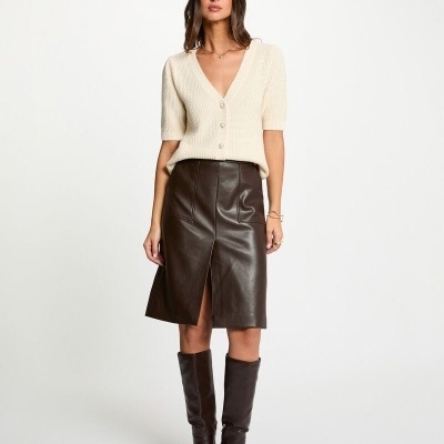 Mulher com casaco creme e saia de couro marrom com botas altas