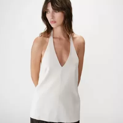 Blusa branca decote em V com calças pretas plissadas em fundo branco