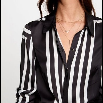 Camisa feminina preta e branca às riscas com colares dourados.