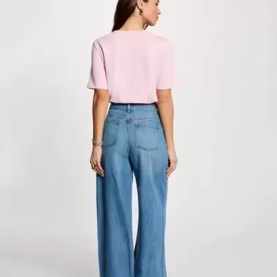 Mulher com t-shirt rosa e calças largas de ganga vista de costas