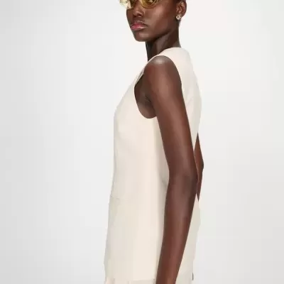 Colete feminino bege claro sem mangas com bolso em fundo branco.