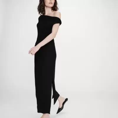 Mulher a usar vestido preto longo com ombro fora, óculos de lentes amarelas e sapatos pretos