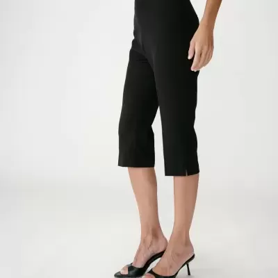 Calças capri pretas femininas com pequena abertura na bainha e sandálias pretas de salto alto