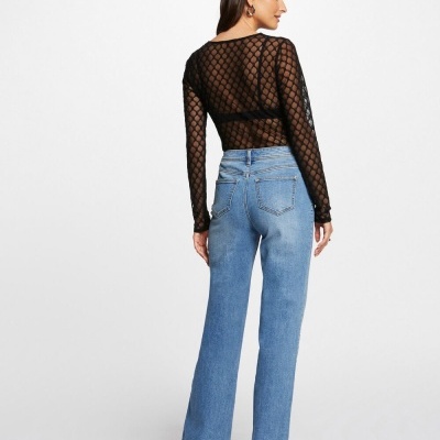 Mulher com blusa preta translúcida e calças de ganga azuis