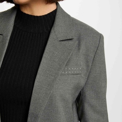 Blazer cinza claro com bolso decorado e camisola preta.