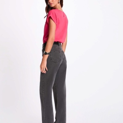 Mulher com calças de ganga cinzentas escuras e t-shirt rosa em fundo branco