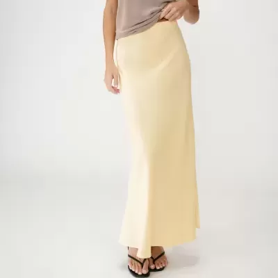 Saia comprida amarela em cetim com top castanho claro e sandálias pretas.