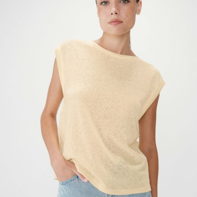 Mulher com t-shirt bege clara sem mangas e jeans azul claro
