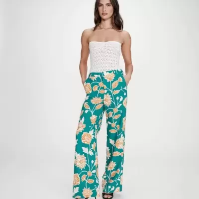 Mulher com top branco de crochet e calças florais verdes e beges