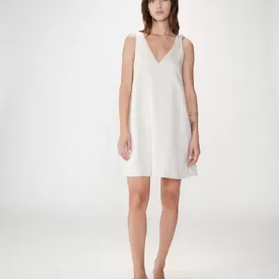 Vestido bege claro de linho ou algodão com alça de nó e sandálias pretas