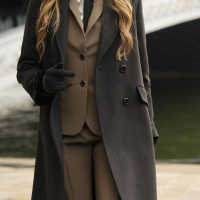 Mulher com casaco preto longo e fato castanho em ambiente exterior