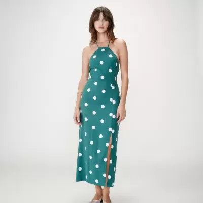 Mulher com vestido verde de bolinhas brancas e decote halter