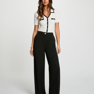 Mulher a usar camisa branca com detalhes pretos e calças largas pretas