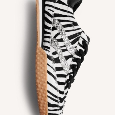 Ténis com padrão zebrado preto e branco e detalhe brilhante prateado.