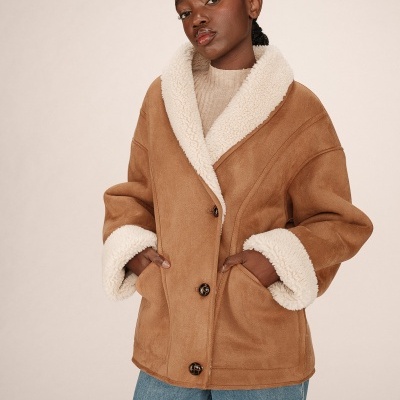 Casaco castanho de tecido camurça com forro branco felpudo e botões frontais.