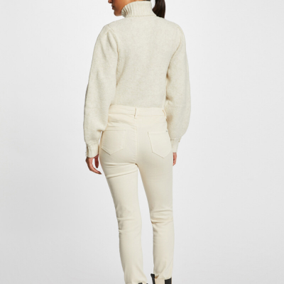 Modelo de costas a usar casaco de malha creme, calças creme e botas bege e pretas em fundo branco