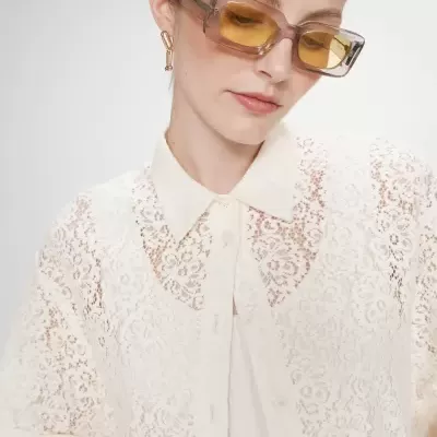 Blusa branca de renda floral com gola e botões, óculos de sol com lentes amarelas