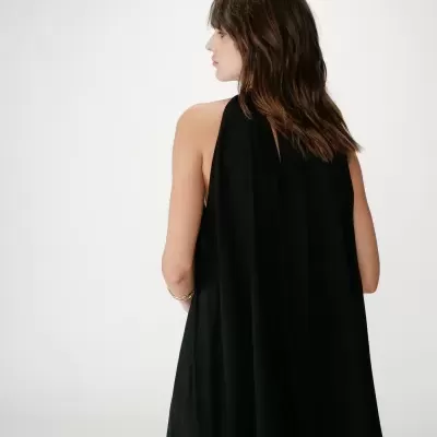 Mulher de costas com vestido preto sem mangas e cabelo castanho ondulado