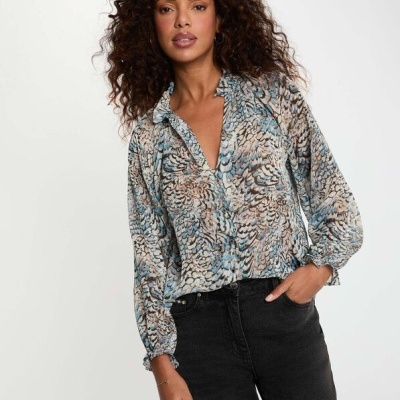 Modelo com blusa de padrão abstrato azul e castanho e calças pretas