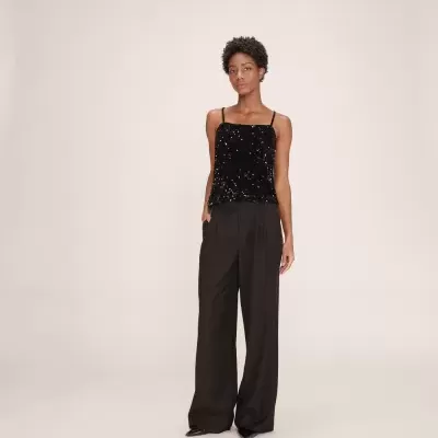 Modelo com top preto de lantejoulas e calças pretas largas